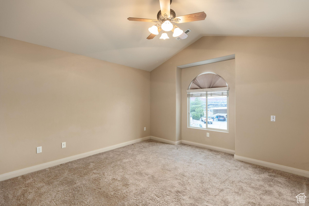 Spare room with lofted ceiling, carpet, baseboards, and ceiling fan
