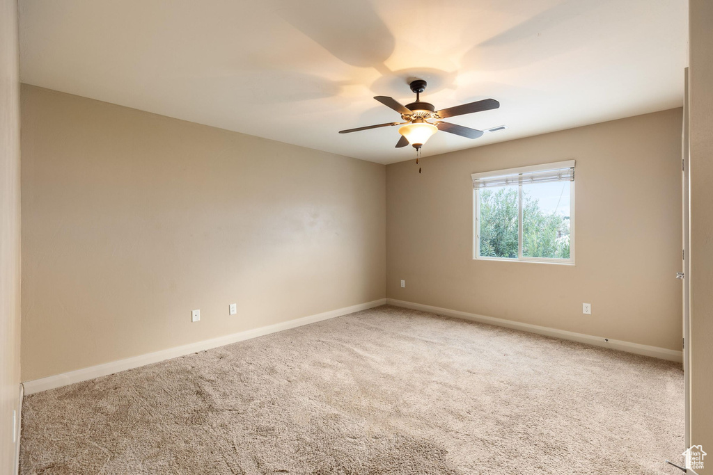 Empty room featuring visible vents, baseboards, carpet, and a ceiling fan