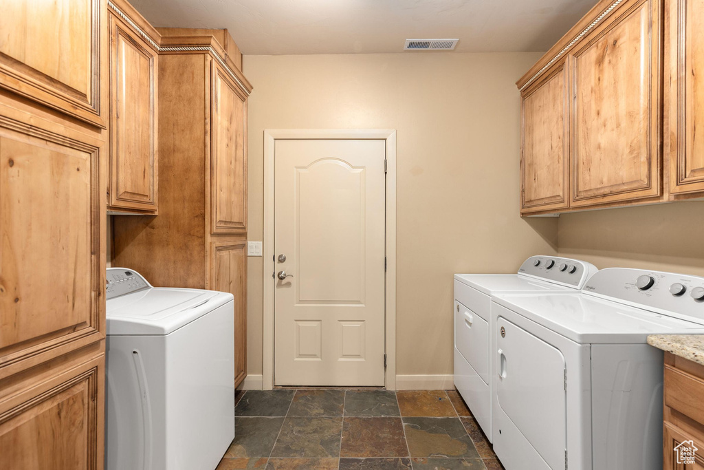Washroom featuring cabinet space, visible vents, and independent washer and dryer