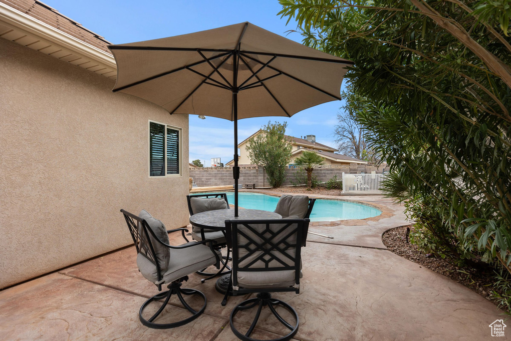 View of patio with outdoor dining area, a fenced backyard, and a fenced in pool