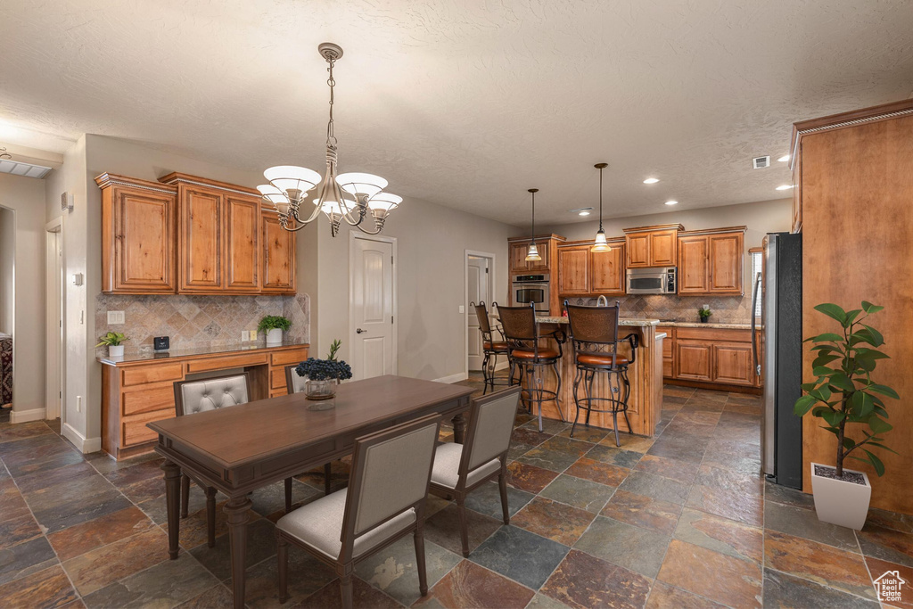 Dining space with baseboards, recessed lighting, stone tile flooring, a textured ceiling, and a chandelier