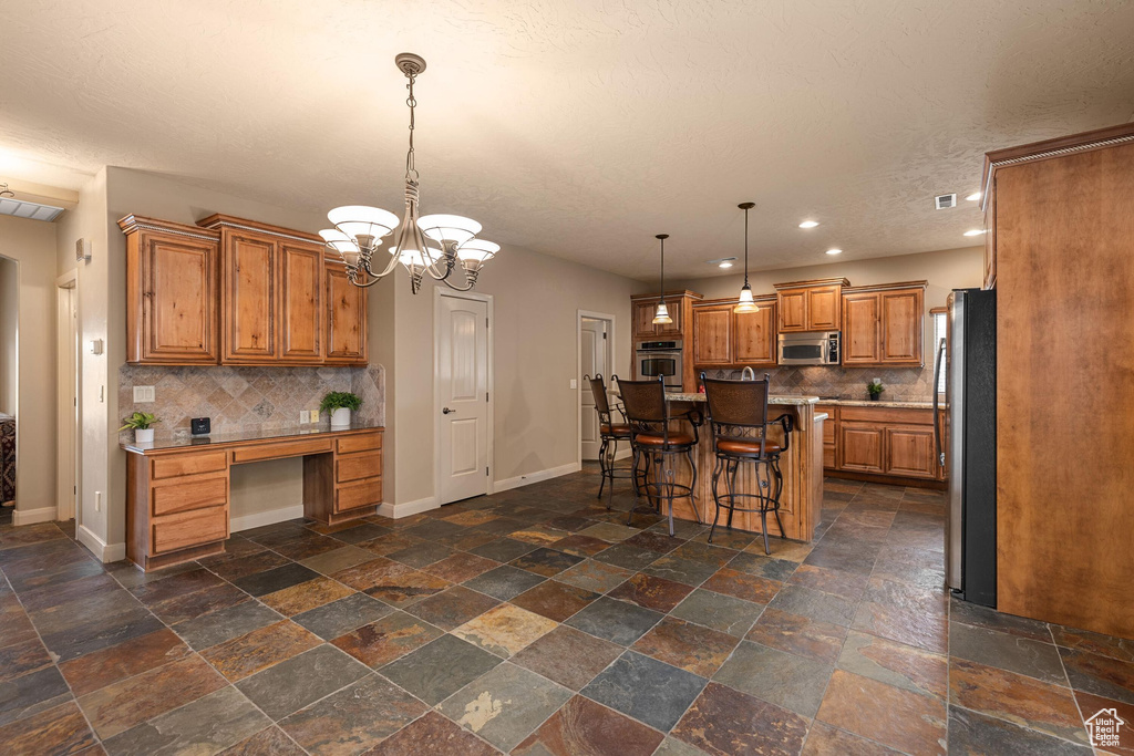 Kitchen with stainless steel appliances, baseboards, tasteful backsplash, and brown cabinetry