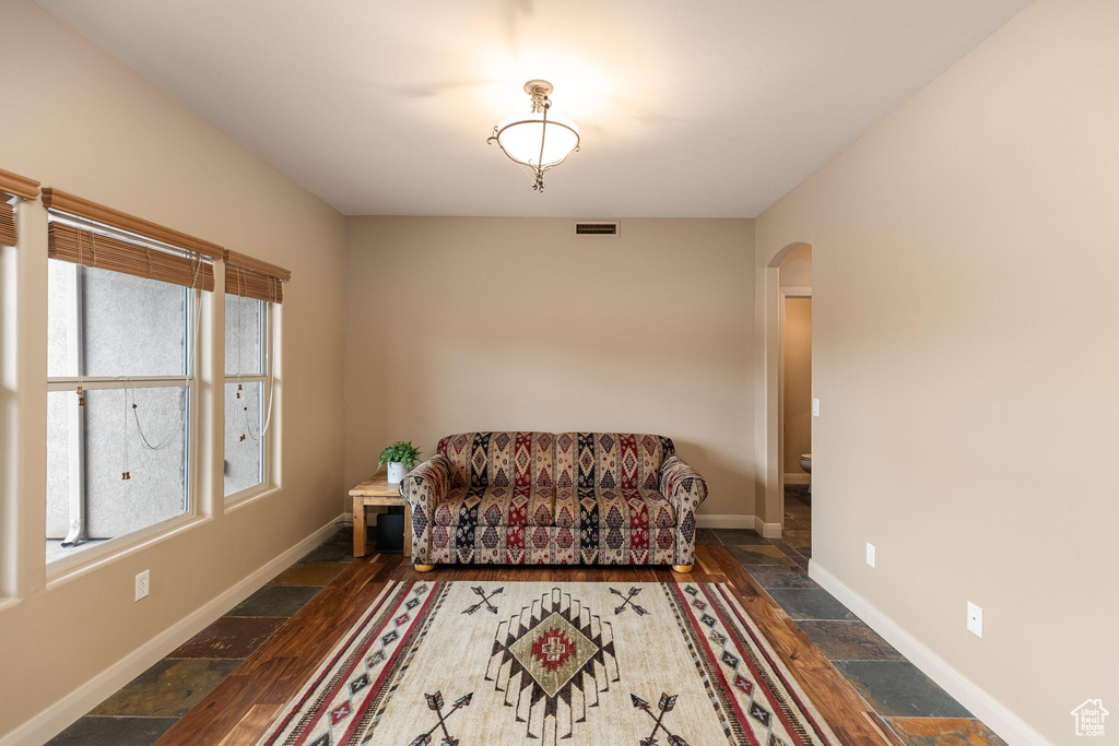 Sitting room with visible vents, arched walkways, baseboards, and stone tile flooring