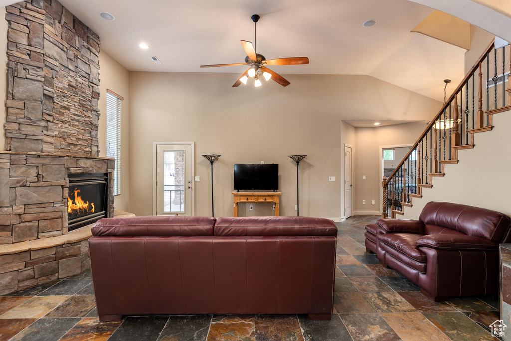 Living area featuring stone tile floors, a fireplace, and ceiling fan