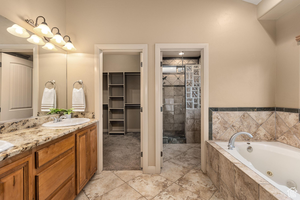 Bathroom with double vanity, a tub with jets, a tile shower, and a sink