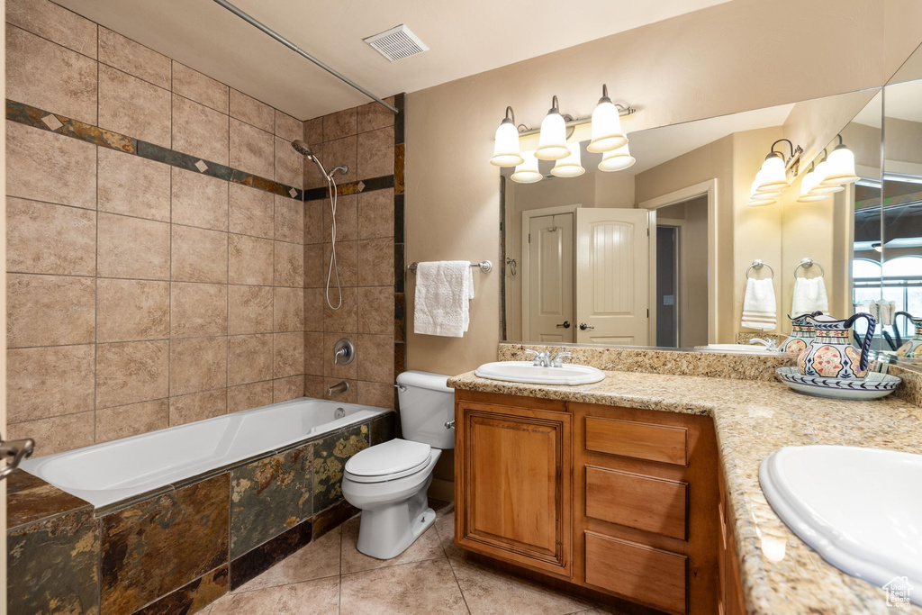 Bathroom with toilet, tiled shower / bath, visible vents, and a sink