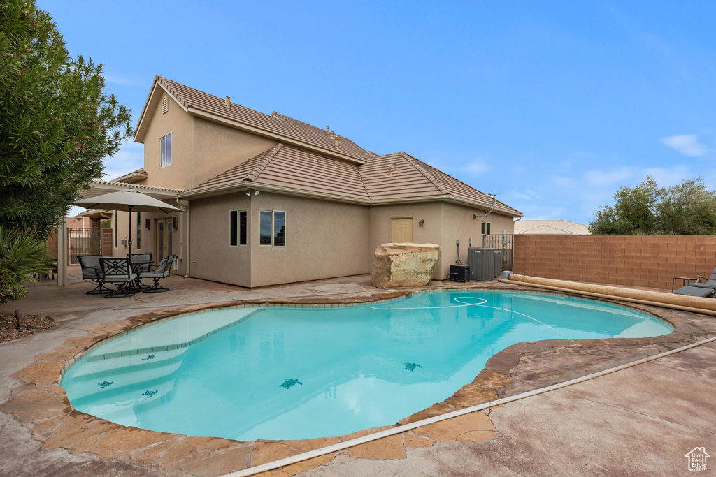 View of pool with a patio area, a fenced in pool, central AC, and fence