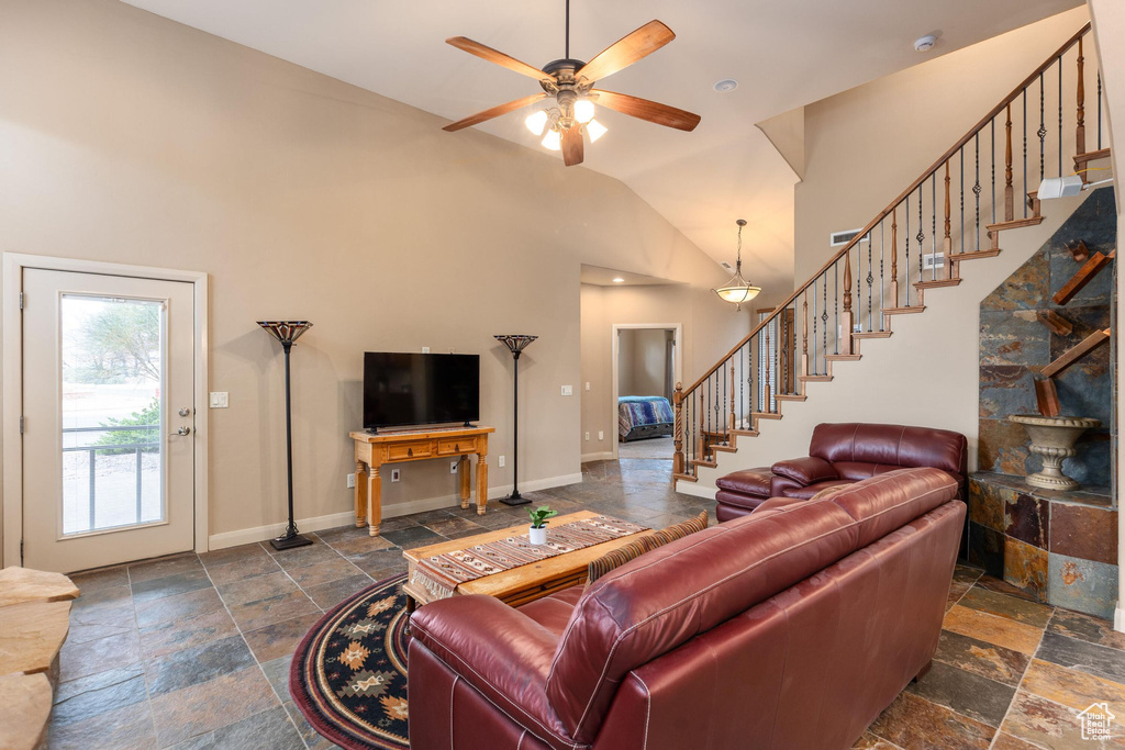 Living room featuring baseboards, a ceiling fan, stone tile floors, and stairs