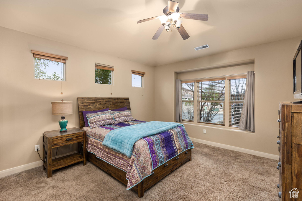 Carpeted bedroom featuring visible vents, baseboards, and ceiling fan