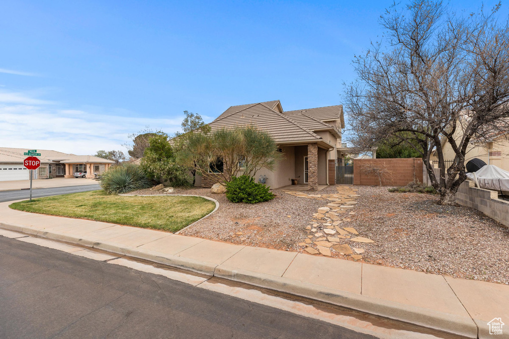 View of front of home with a tiled roof, a gate, fence, and stucco siding