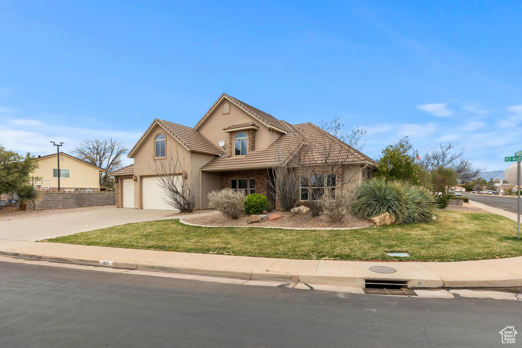 View of front facade featuring stucco siding, a front lawn, driveway, an attached garage, and a tiled roof