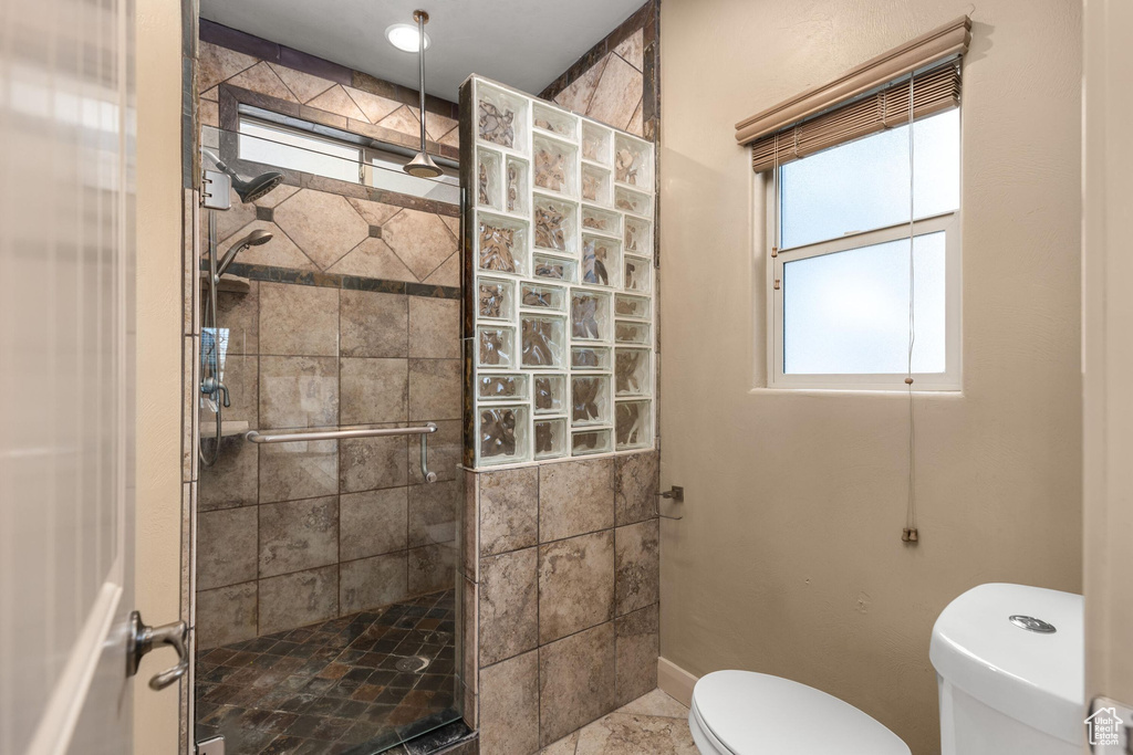 Bathroom featuring a stall shower, toilet, and baseboards