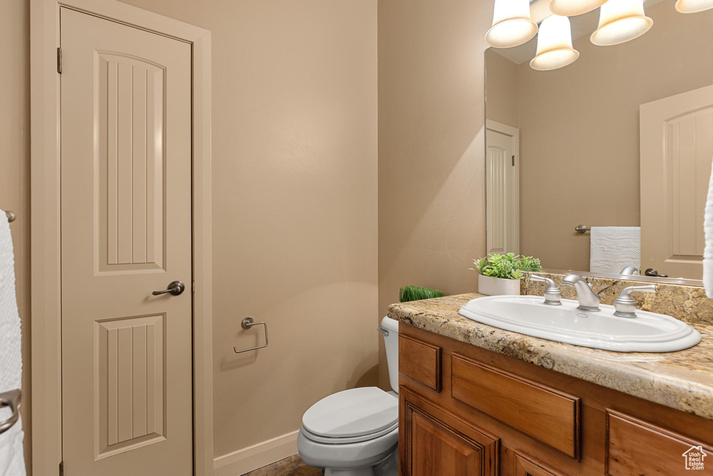 Half bathroom with vanity, toilet, and baseboards
