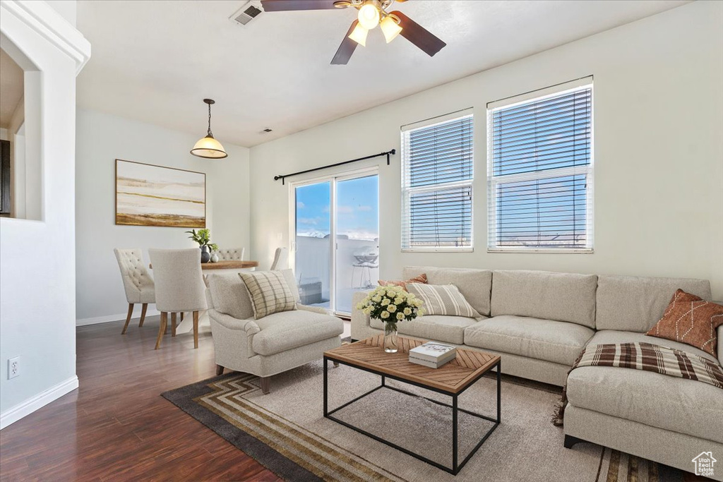 Living area featuring dark wood-style floors, ceiling fan, baseboards, and arched walkways