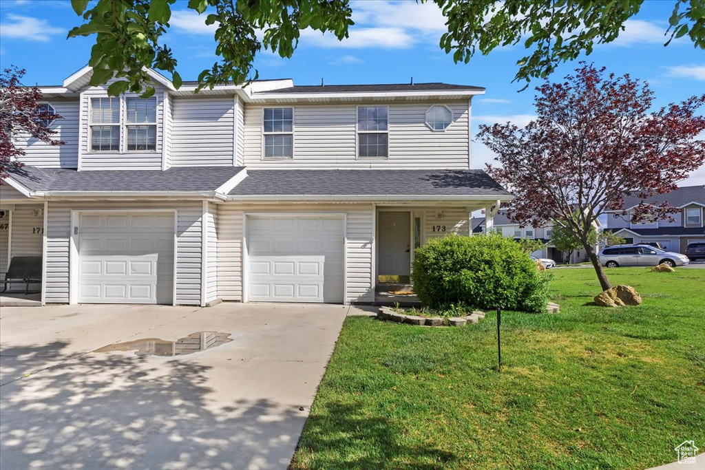 Multi unit property featuring driveway, a garage, and a front yard