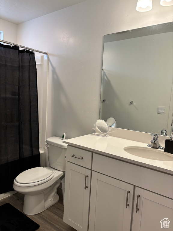Bathroom featuring vanity, toilet, wood finished floors, and shower / bath combo