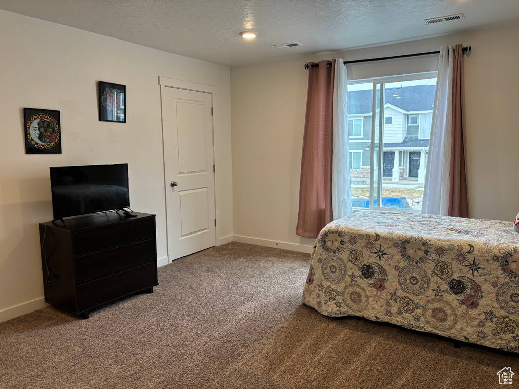 Carpeted bedroom featuring baseboards, visible vents, and a textured ceiling