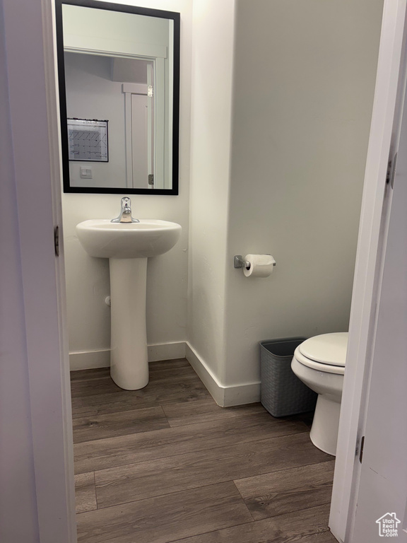 Bathroom featuring toilet, wood finished floors, and baseboards
