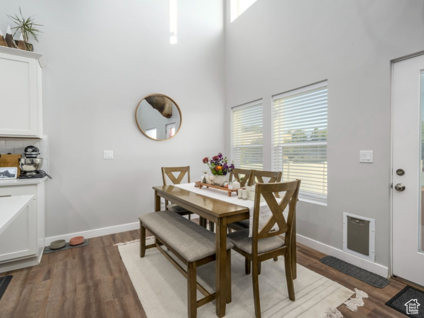 Dining space featuring a high ceiling, wood finished floors, and baseboards