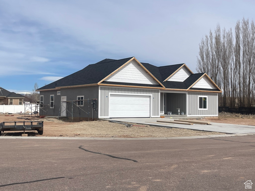 View of front of house featuring an attached garage, driveway, and fence