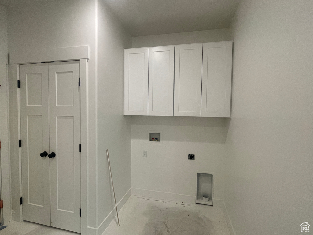 Clothes washing area featuring baseboards, cabinet space, hookup for an electric dryer, and washer hookup