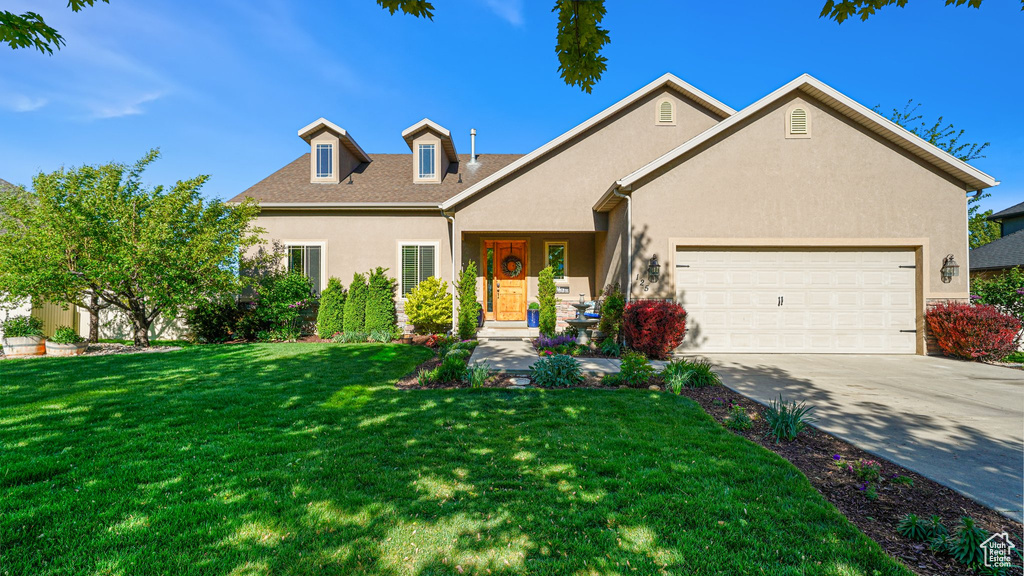 Traditional-style house with stucco siding, a garage, driveway, and a front yard