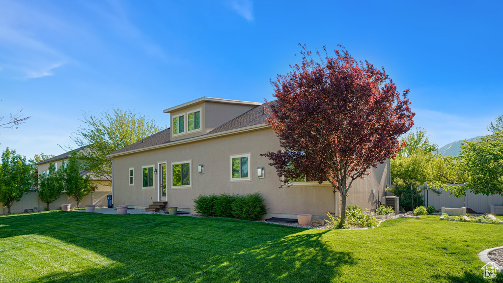 Rear view of house featuring entry steps, stucco siding, central AC unit, and a shingled roof