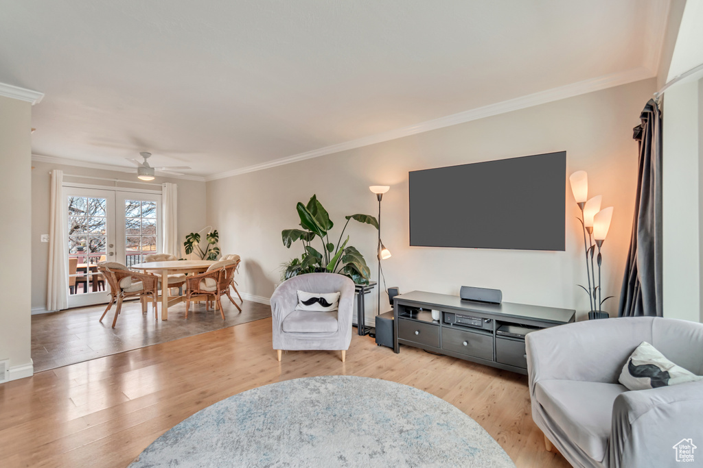 Living room featuring baseboards, light wood-type flooring, a ceiling fan, and ornamental molding