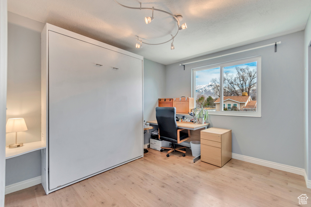 Office space with baseboards, rail lighting, and light wood finished floors