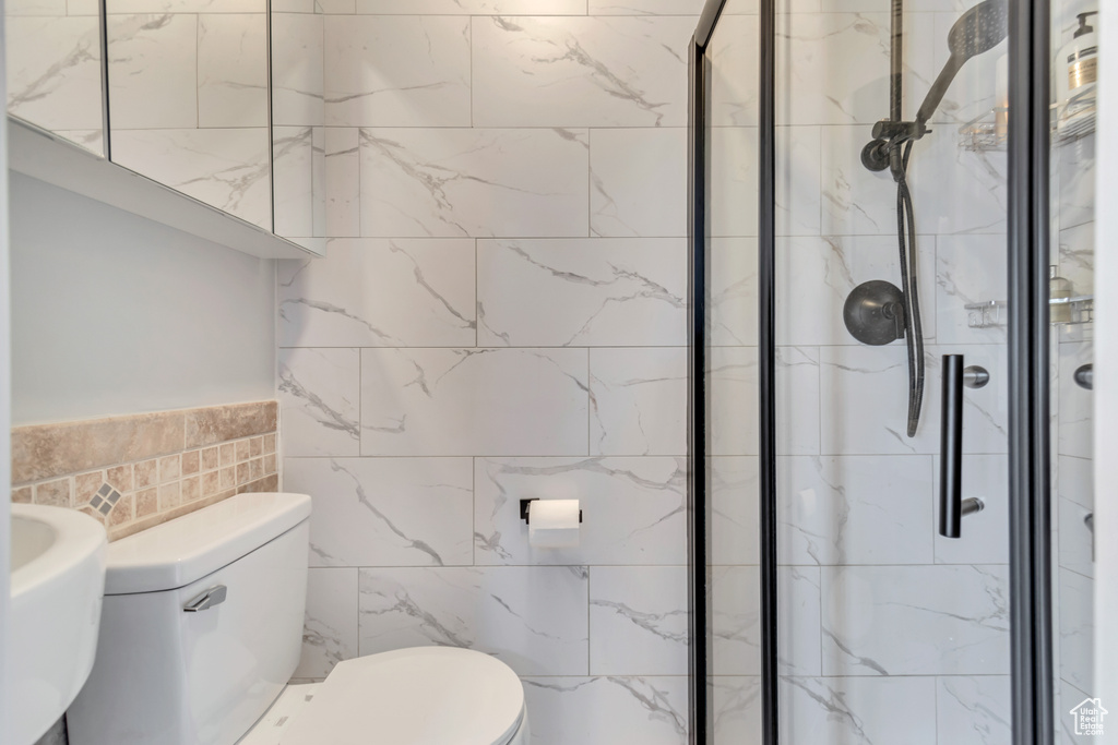 Full bathroom featuring toilet, tile walls, and a shower stall
