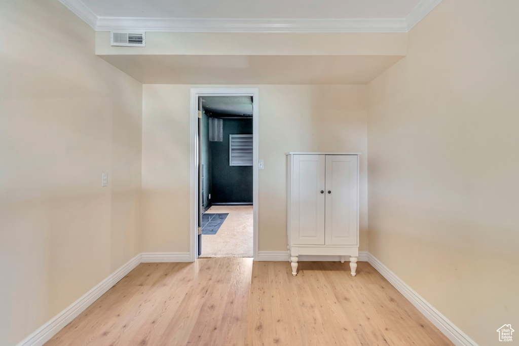 Unfurnished room featuring crown molding, baseboards, visible vents, and light wood finished floors