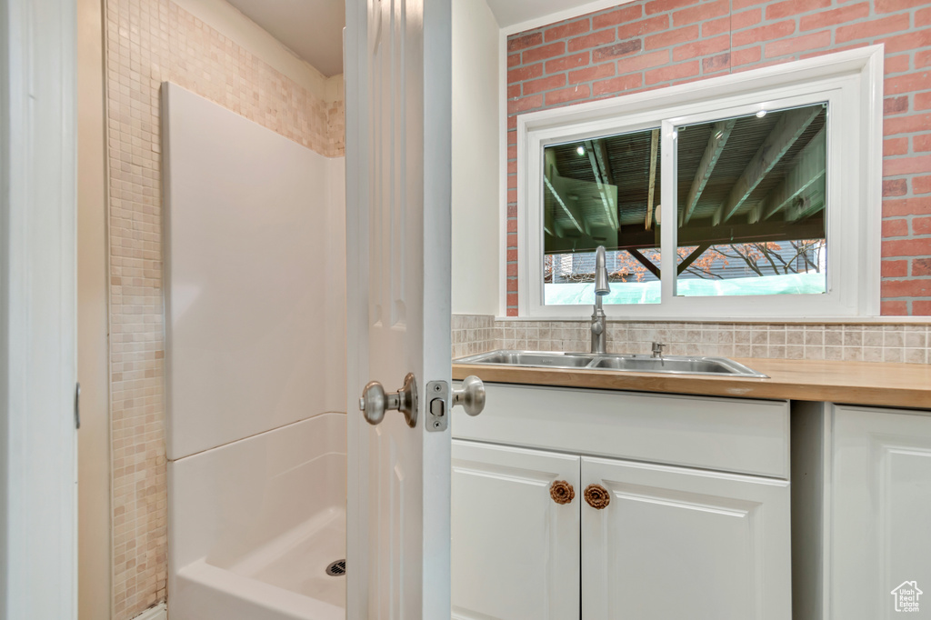 Bathroom featuring vanity, brick wall, and walk in shower