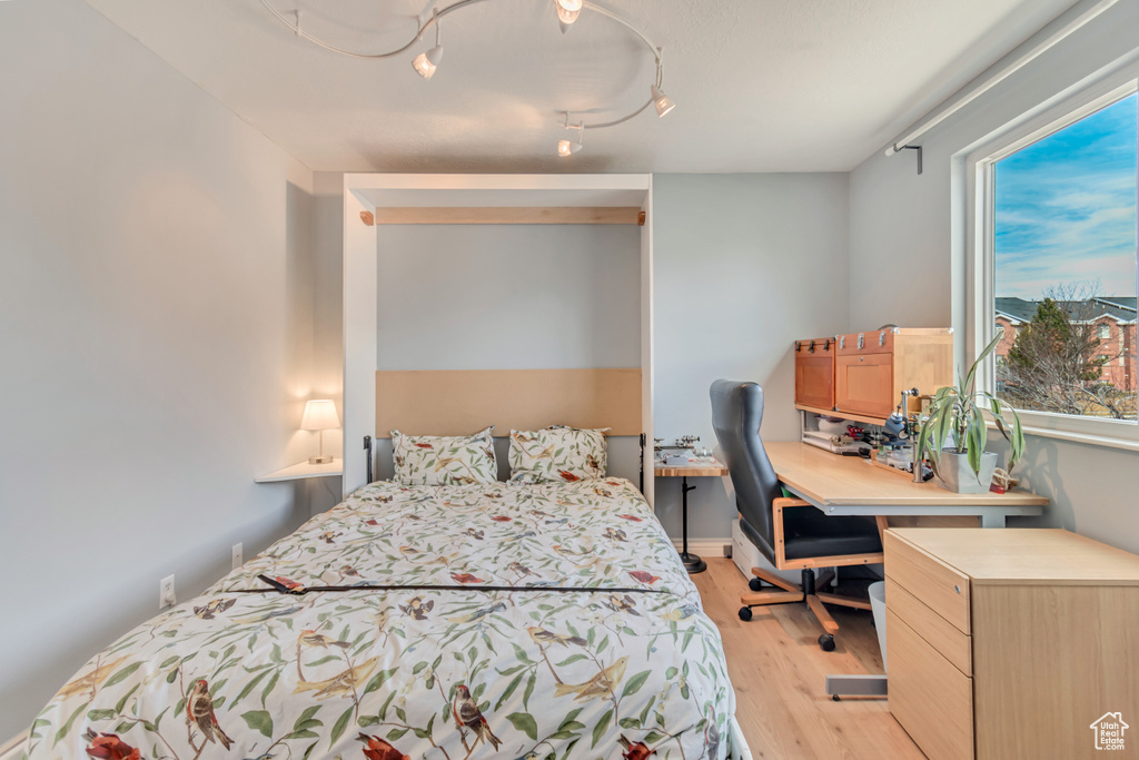 Bedroom with light wood-style flooring and track lighting