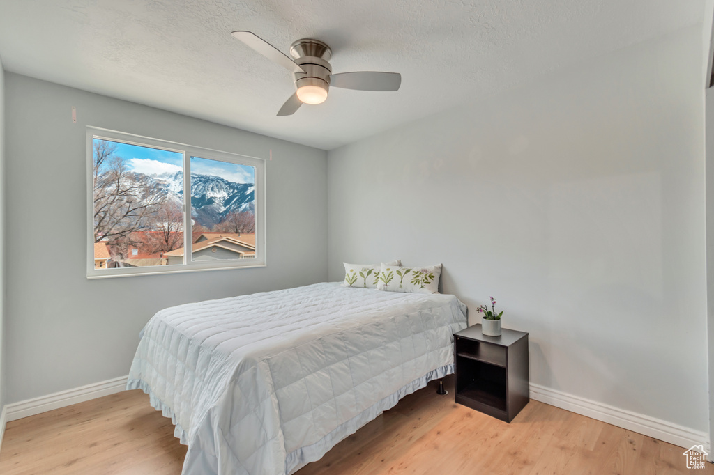 Bedroom with ceiling fan, baseboards, a textured ceiling, and wood finished floors