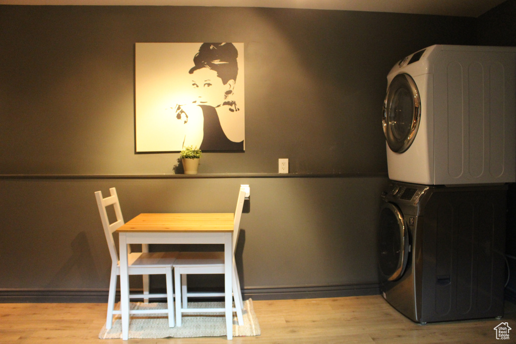 Washroom featuring laundry area, wood finished floors, and stacked washer and clothes dryer