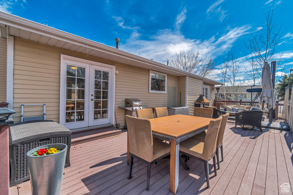 Wooden terrace featuring french doors, area for grilling, and outdoor dining space
