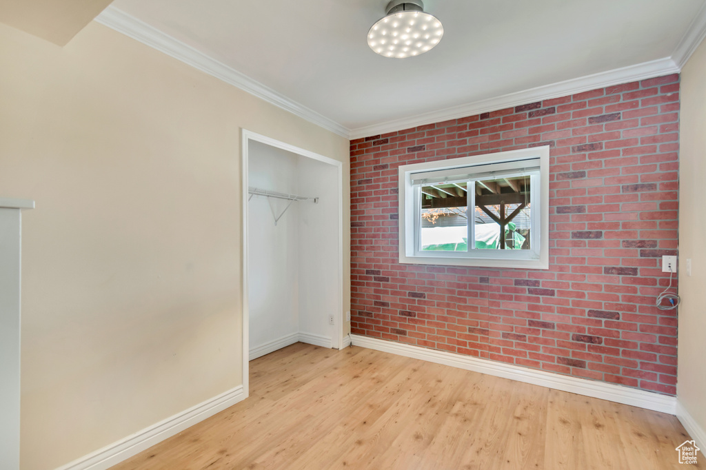 Unfurnished bedroom with a closet, baseboards, light wood-style floors, and crown molding