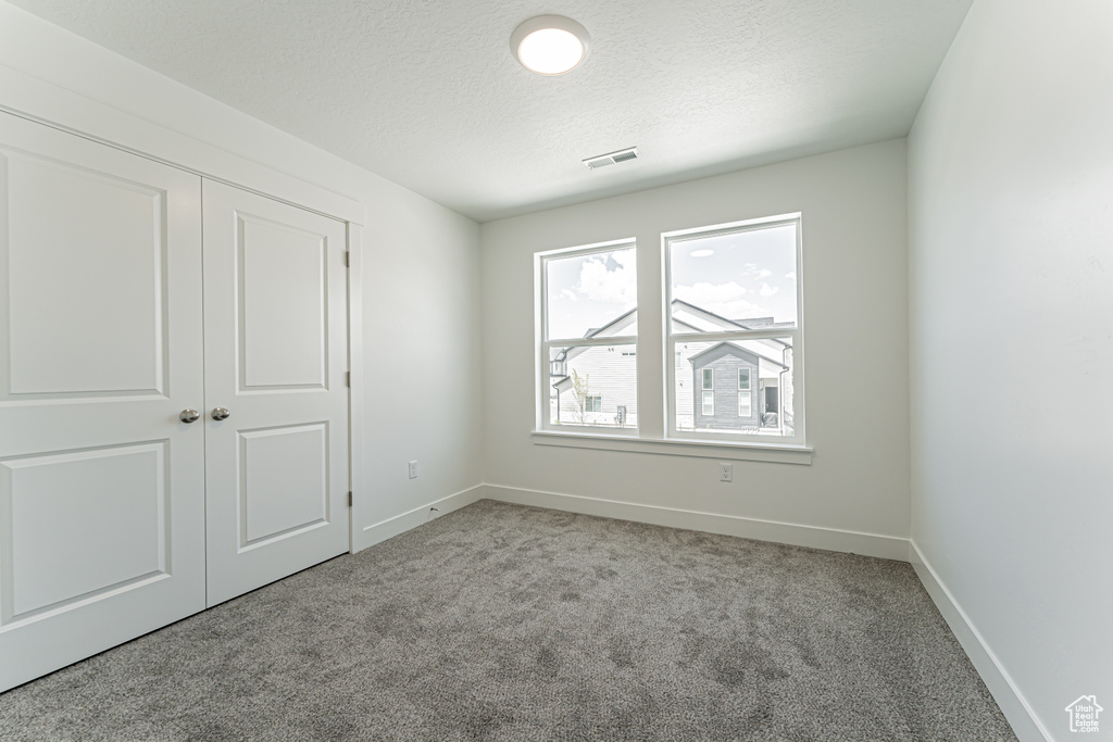Unfurnished bedroom with carpet floors, a textured ceiling, and a closet