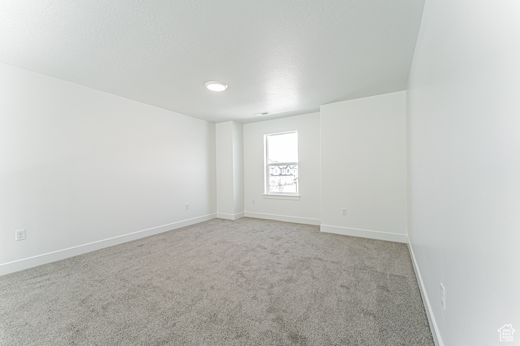 Carpeted spare room with baseboards and a textured ceiling