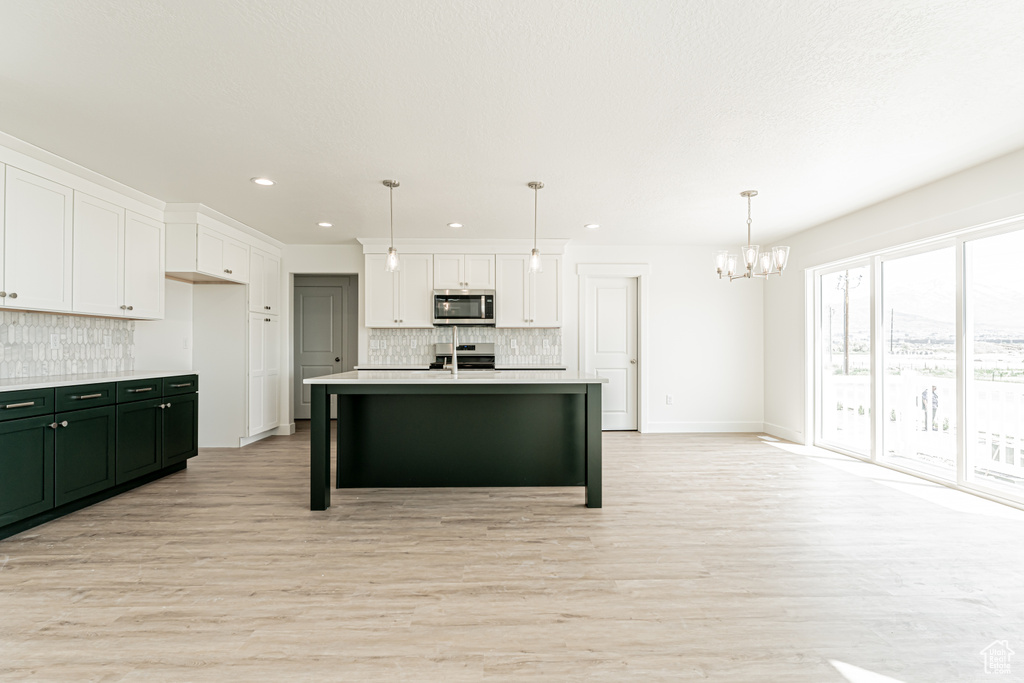 Kitchen with stainless steel microwave, a chandelier, backsplash, white cabinetry, and black / electric stove
