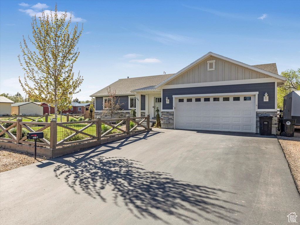 Ranch-style house featuring stone siding, asphalt driveway, an attached garage, and board and batten siding