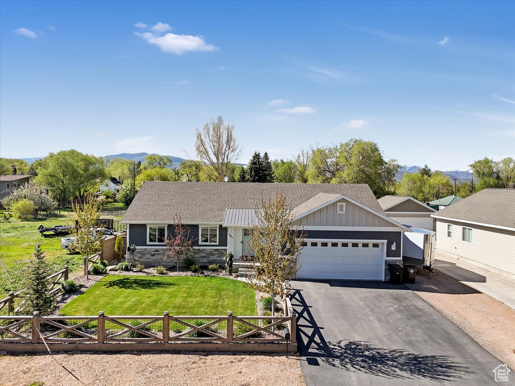 Single story home with board and batten siding, an attached garage, roof with shingles, driveway, and a mountain view