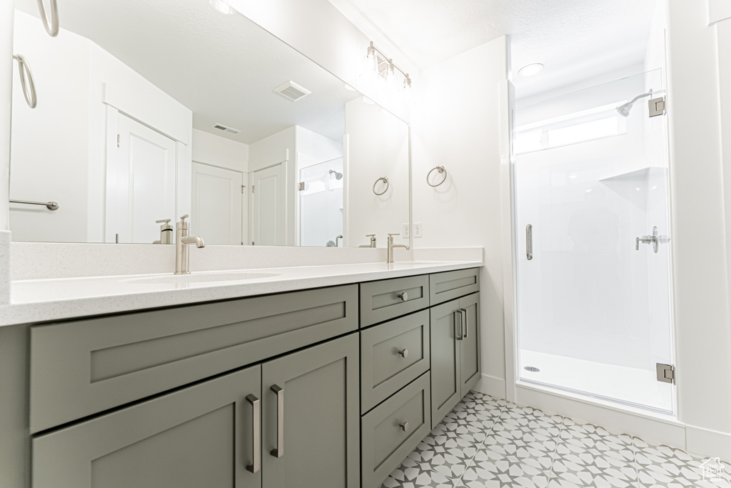 Bathroom featuring double vanity, a stall shower, and tile patterned floors