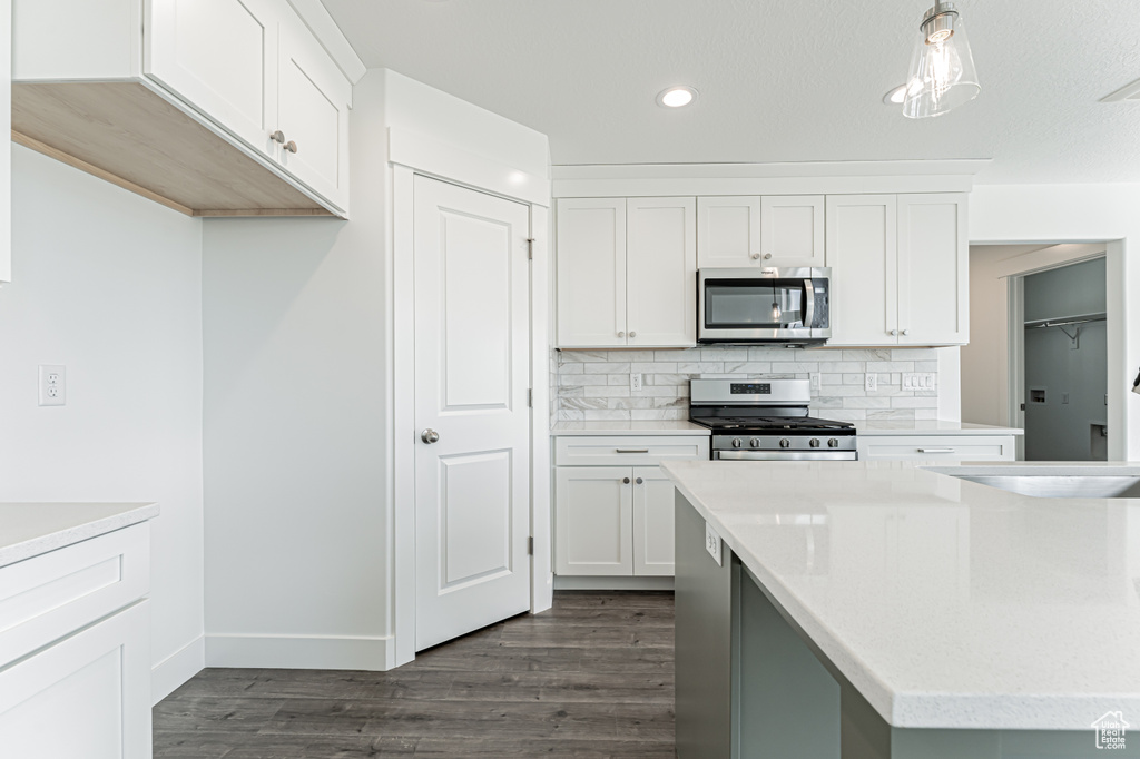 Kitchen with appliances with stainless steel finishes, dark wood-style flooring, light countertops, tasteful backsplash, and recessed lighting