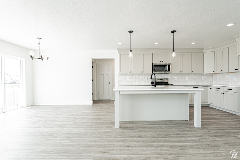 Kitchen with appliances with stainless steel finishes, light countertops, a chandelier, backsplash, and recessed lighting