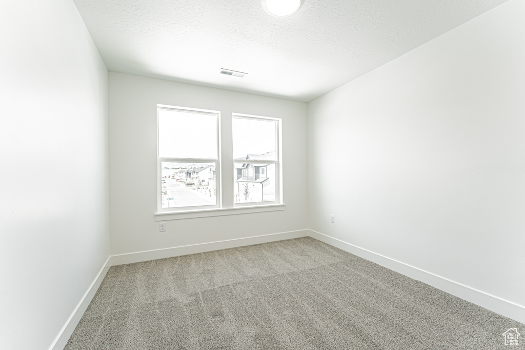 Carpeted spare room featuring a textured ceiling