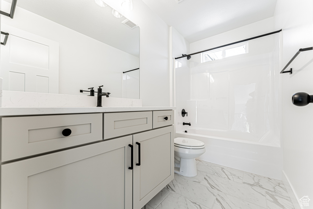 Bathroom featuring shower / bath combination, vanity, and marble look tile flooring