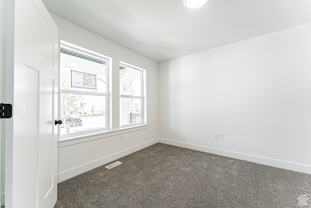 Spare room with dark carpet and a textured ceiling