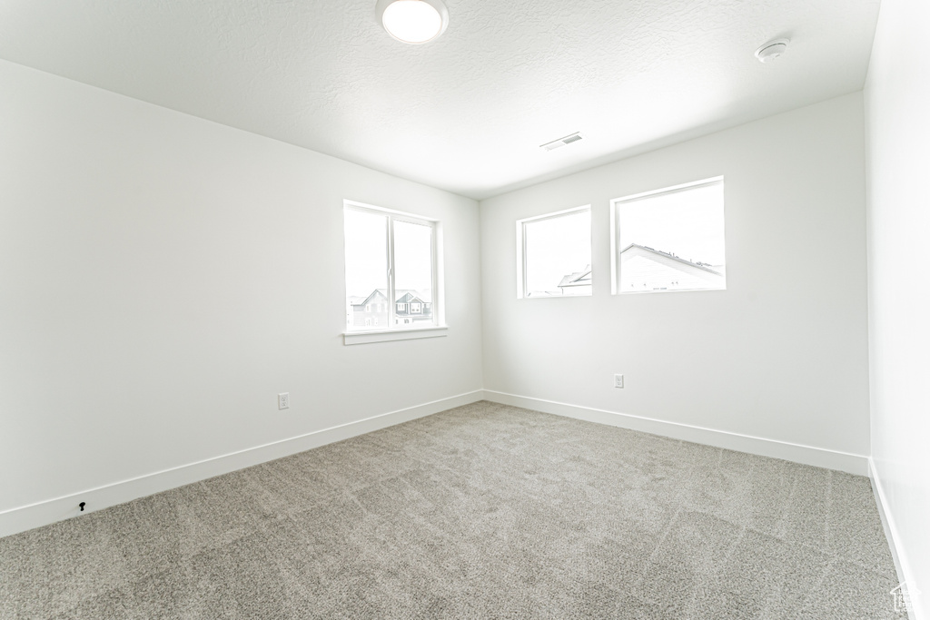 Empty room featuring carpet floors and a smoke detector