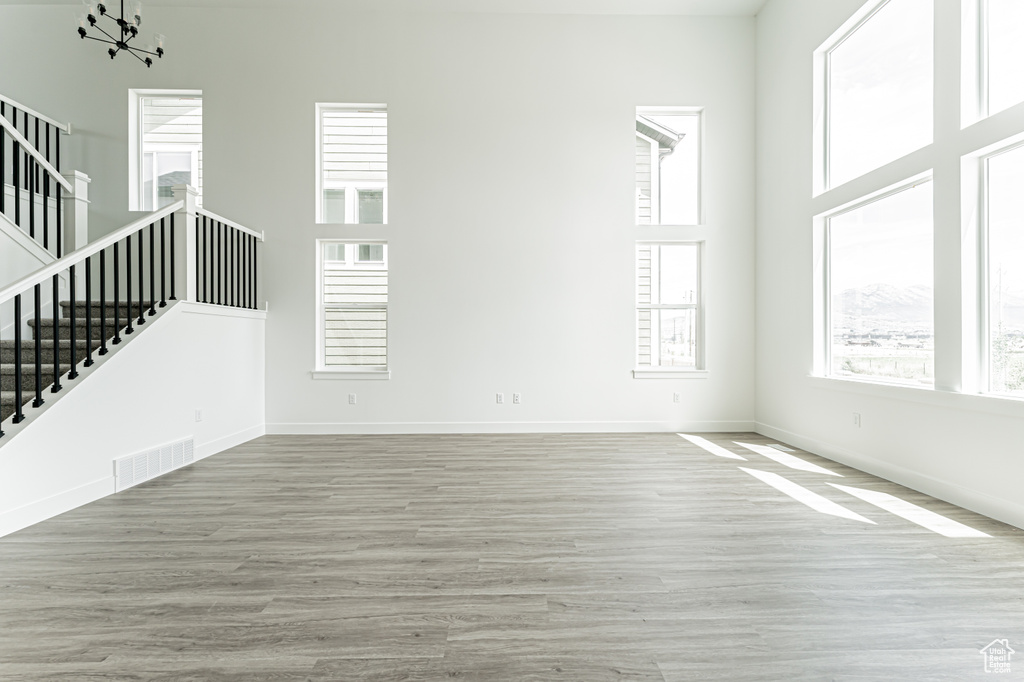 Spare room featuring stairs, healthy amount of natural light, wood finished floors, and a high ceiling